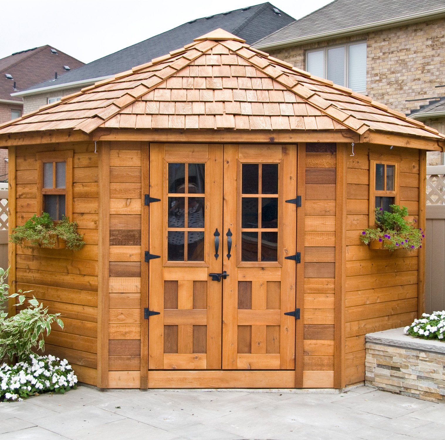 Front view of the Outdoor Living Today Penthouse Garden Shed. The flower boxes of this corner shed are decorated with flowers.