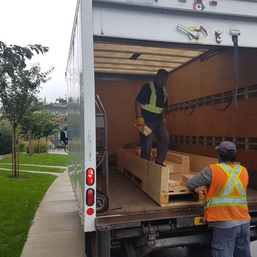 Two men unloading a package from an 18 wheeler truck